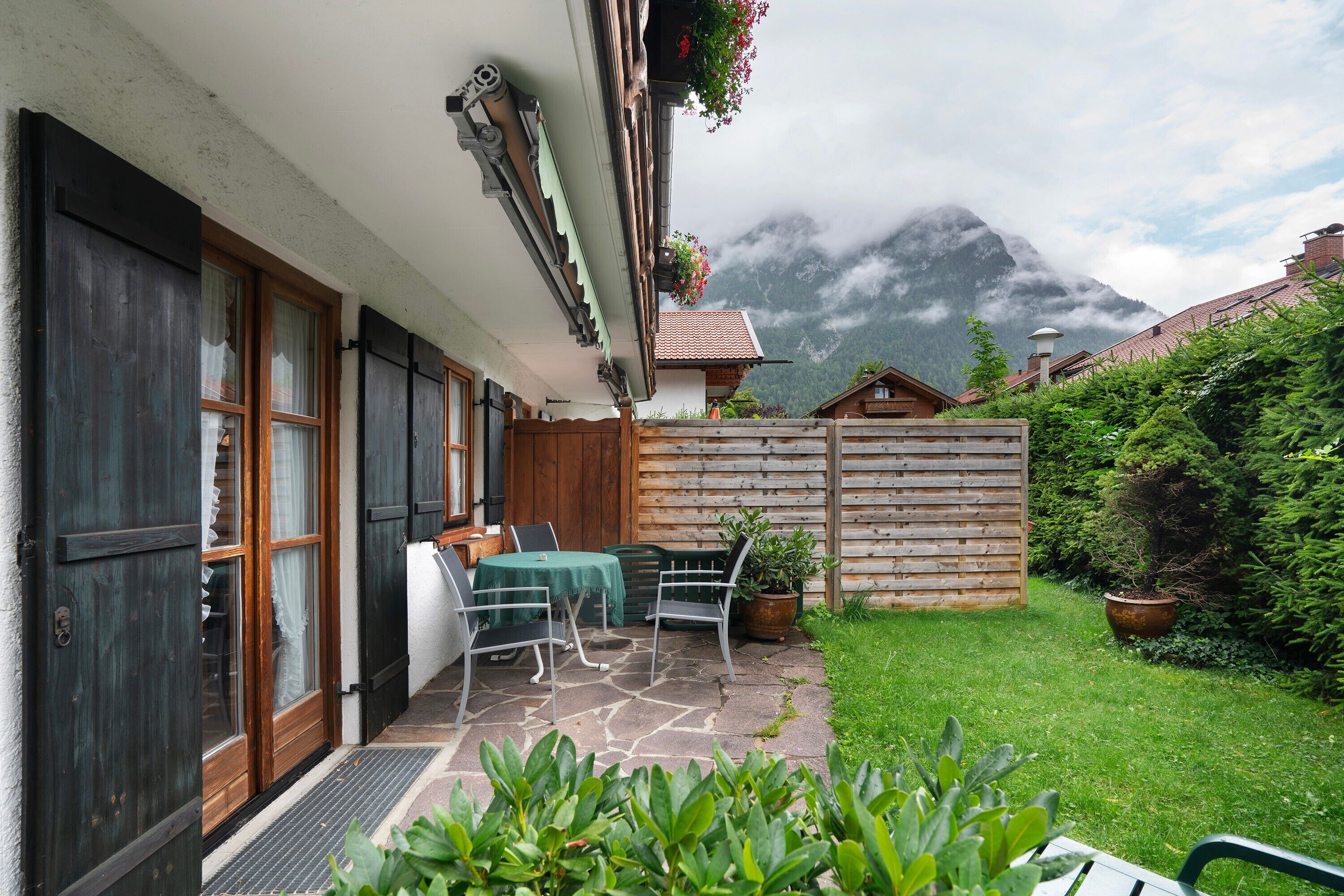 A patio with outdoor furniture, a wooden fence, and a mountain backdrop.