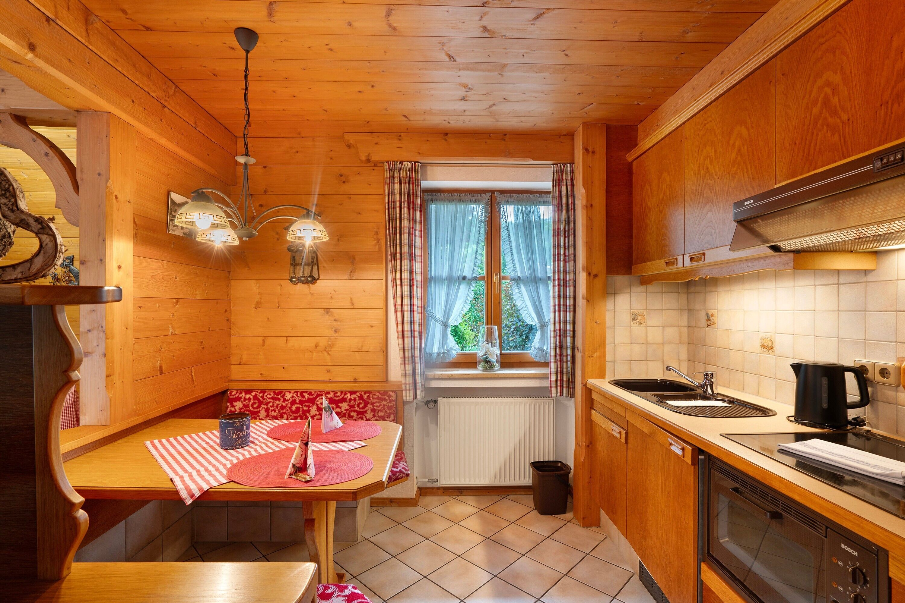 Ein Holzblock-Innenraum mit Essbereich, Küche und einem Fenster mit Vorhängen.