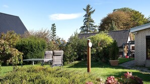A garden with a barbecue grill, two chairs, and a potted plant.