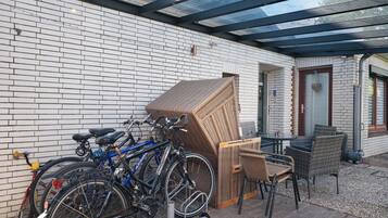 Un espace extérieur abrité, doté d’un mur en briques, de vélos, de meubles en osier et d’un toit en verre.