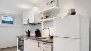 Une cuisine moderne avec des meubles blancs, un four encastré, un évier et un plan de travail.
