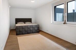 Ein Schlafzimmer mit Bett, Fenster und Holzboden.
