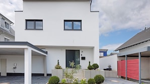 Une maison moderne à deux étages, dotée d’une entrée à l’avant, d’un garage et d’un jardin bien entretenu.