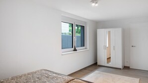Une chambre à coucher avec un lit, une fenêtre, une armoire et une porte.