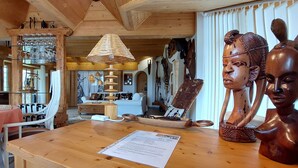 A wooden interior with a dining table, chairs, a lamp, and various decorative items.