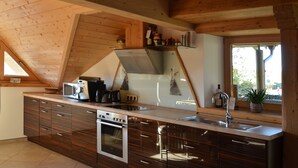 A modern kitchen with wooden beams, a built-in oven, and a large island with a sink.