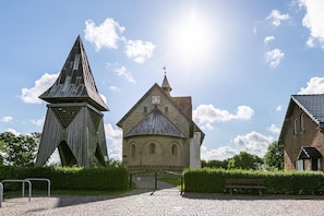 Een kerk met een klokkentoren, een geplaveid pad en een bankje.