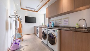 A modern laundry area with a washing machine, dryer, and a drying rack.