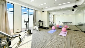 A gym with exercise equipment, large windows, and a mirrored wall.