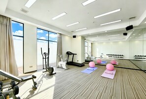 A gym with exercise equipment, large windows, and a mirrored wall.