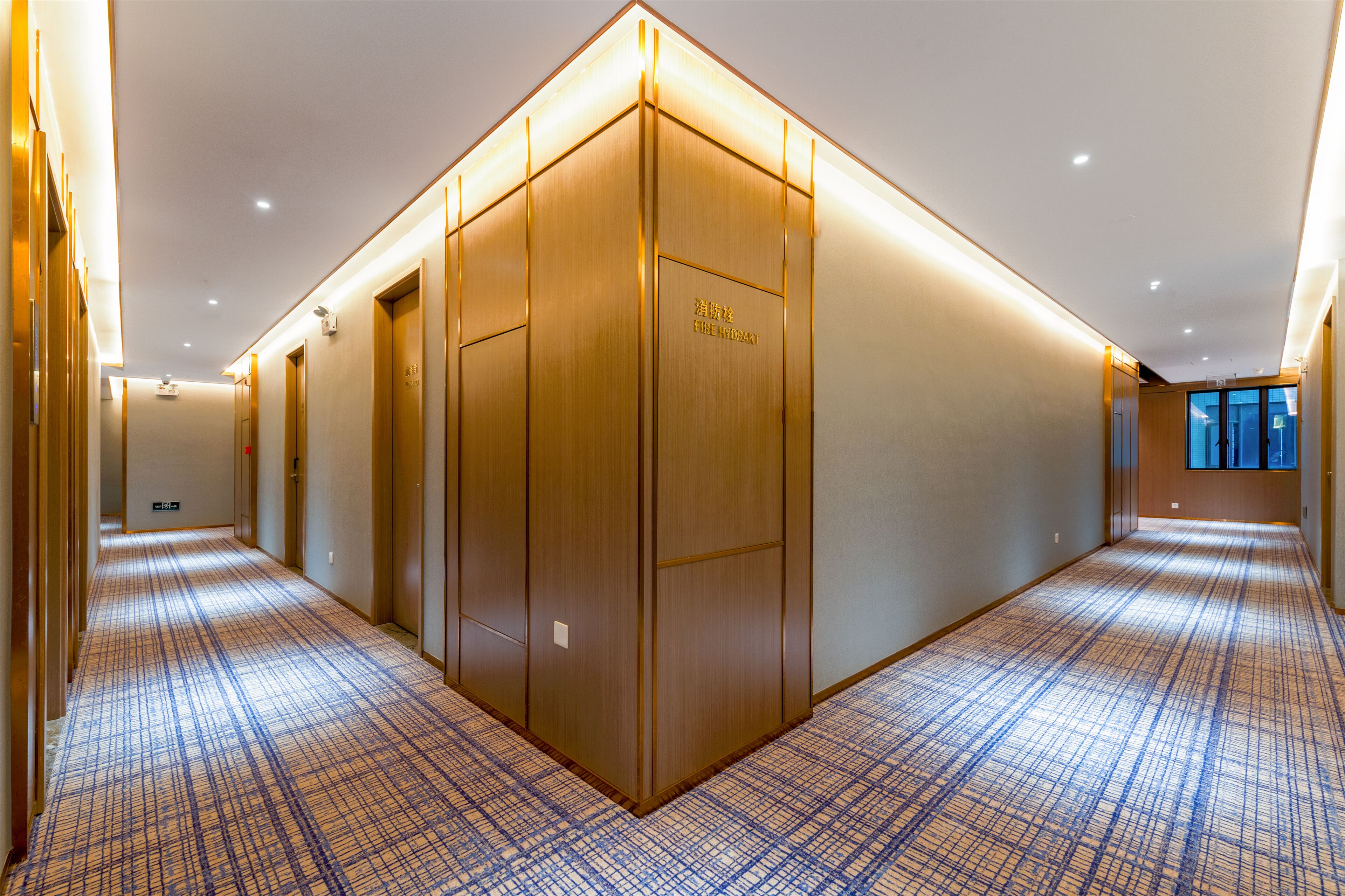 A hotel hallway with a checkered floor pattern, wooden doors, and a fire hydrant sign on one door.