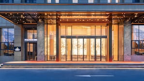 A hotel entrance with a glass door, a sign above the door, and a lighted pathway leading to the entrance.