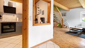 A modern kitchen with a built-in oven and a dining area with a wooden staircase. - Apartment 'Inge Huus' with Private Terrace, Garden, and Wi-Fi (Hude)
