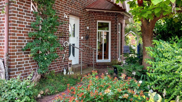A brick house with a garden, a bird feeder, and a door. - Apartment 'Inge Huus' with Private Terrace, Garden, and Wi-Fi (Hude)