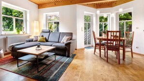 A living room with a sofa, coffee table, and dining table with chairs. - Apartment 'Inge Huus' with Private Terrace, Garden, and Wi-Fi (Hude)