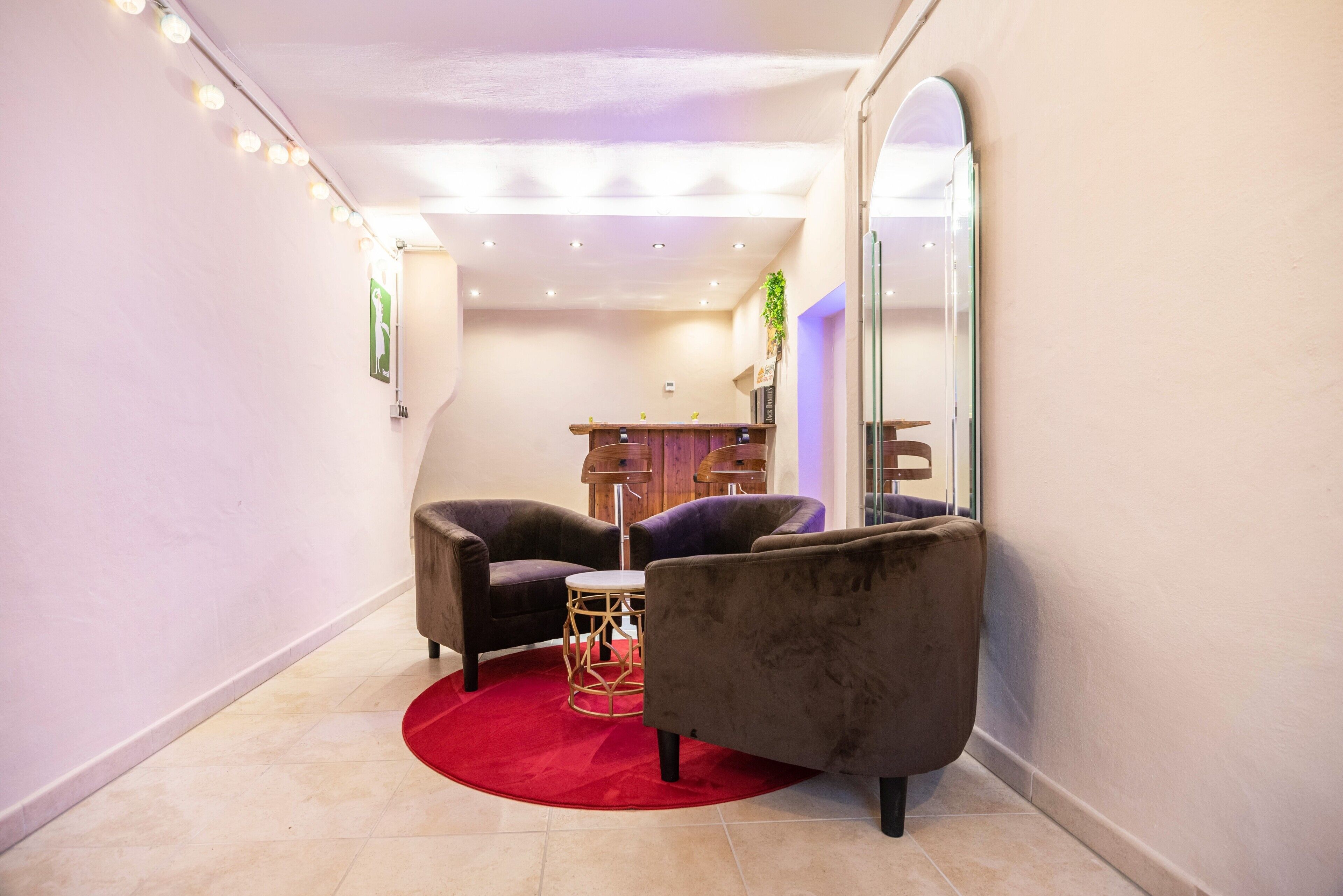 A modern room with two armchairs, a small round table, a red rug, and a large mirror.