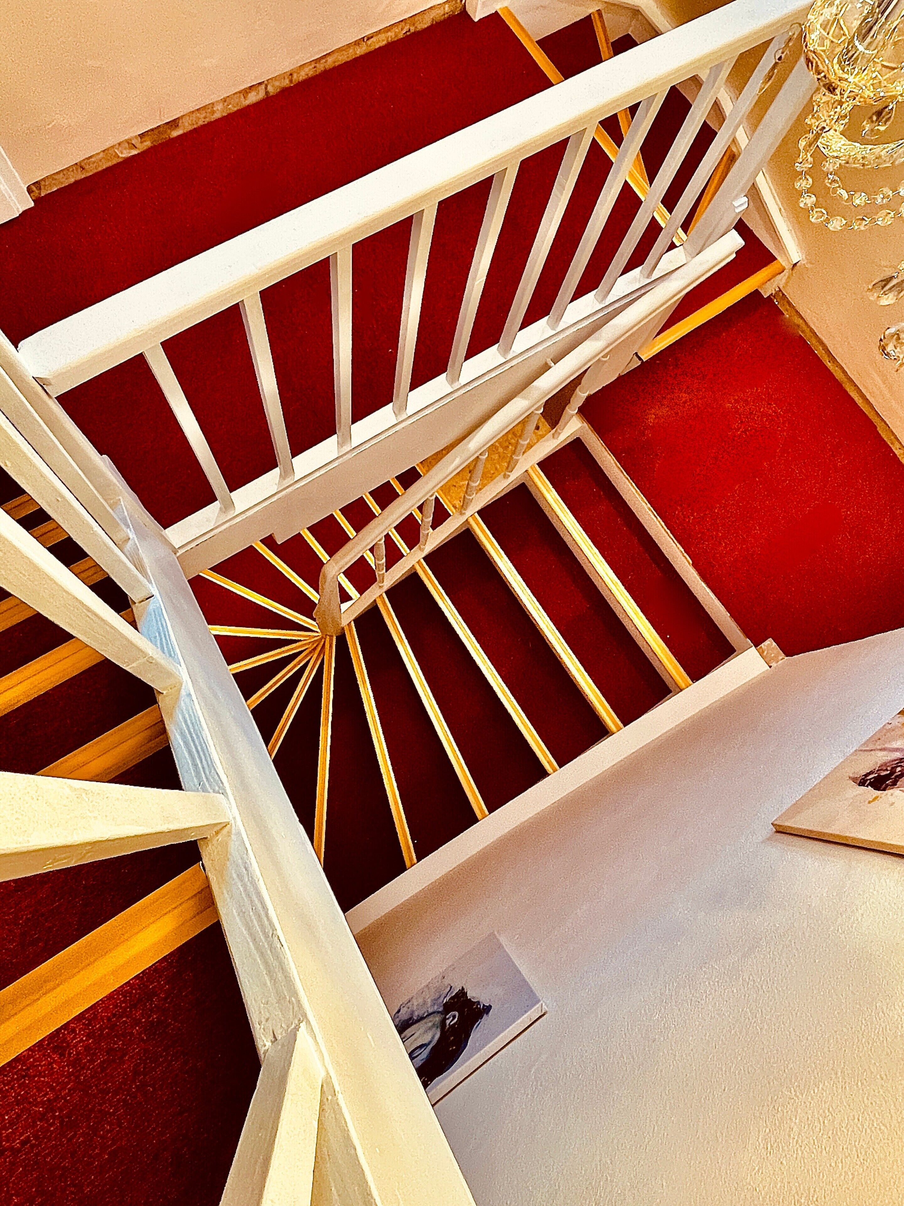 Eine Wendeltreppe mit weißen Geländern und einem roten Teppich.