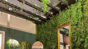 Una habitación con una pared verde, un sillón marrón y dos espejos.