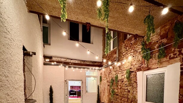 Un interior acogedor con suelo de madera, un sofá marrón y luces de tipo guirnalda.