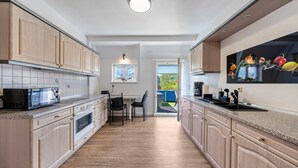 A modern kitchen with wooden cabinets, a dining area with chairs, and a view through the door. - Carpe Diem Apartment with Shared Garden and Wi-Fi (Görlitz)