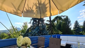 A patio with a table, chairs, a vase of flowers, and a view of trees and mountains. - Carpe Diem Apartment with Shared Garden and Wi-Fi (Görlitz)