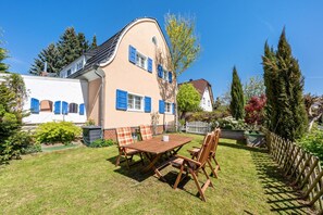 Une maison avec un toit incurvé, une table et des chaises en bois, et une cour clôturée.