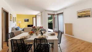 A dining area with a table set for four, surrounded by black chairs, a vase with flowers, and a bowl of fruit. - Il Giardino di Riva - Garden Apartment Near the Lake (Riva del Garda)