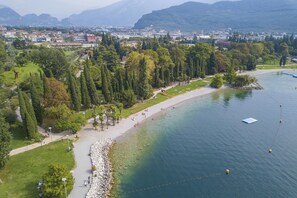 A riverside park with walking paths, a beach, and a view of a city in the background. - Il Giardino di Riva (Riva del Garda)