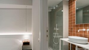 Un baño moderno con cabina de ducha de vidrio, un lavabo blanco y un espejo grande.