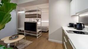 Una habitación compacta y moderna con una cama litera, una pequeña kitchenette y un rascador para gatos.
