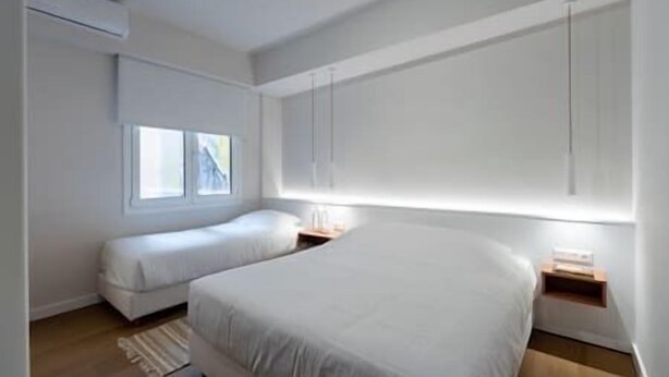 Un dormitorio moderno con una cama grande, una cama más pequeña y una ventana.