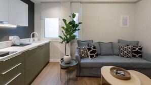 Una sala de estar moderna con un sofá gris, una mesita auxiliar y una planta en maceta.