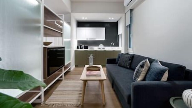 Un espace de vie compact comprenant un coin cuisine, un canapé et une petite table.