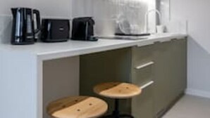 A modern kitchen with a white countertop, a coffee maker, a toaster, and two stools. - Central Bliss Suite D1 (Athens)