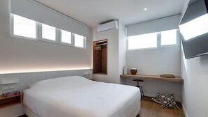 A modern bedroom with a large bed, a bedside table, a small stool, and a window with a view. - Central Bliss Suite D1 (Athens)