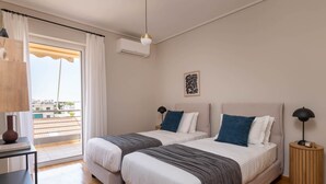 Une chambre d’hôtel avec deux lits, une petite table, une lampe et une vue sur la ville.