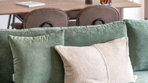 A modern living room with a green sofa, a dining table with chairs, and abstract wall art. - Vibrant Living in Chalandri (Chalandri)