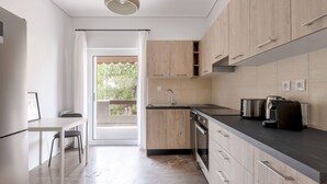 A modern kitchen with wooden cabinets, a black countertop, and a built-in oven. - Vibrant Living in Chalandri (Chalandri)
