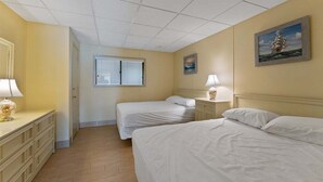 Ein Hotelzimmer mit zwei Betten, einem Schminktisch, einem Fenster und einem Bild an der Wand.