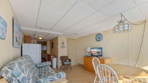 Ein gemütliches Wohnzimmer mit Sofa, Esstisch, Stühlen, Fernseher und einer dekorativen Wanduhr.