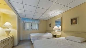 Une chambre d’hôtel avec deux lits, une commode, un miroir et une fenêtre avec des stores.