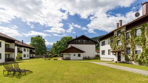 A courtyard with a grassy lawn, outdoor seating, and buildings with balconies and windows. - Vacation apartment Schanzenblick C8 (Oberaudorf)