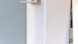 Een deur met een numeriek keypad slot en een normale deurklink.