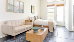 Een moderne slaapkamer met een bed, een slaapbank, een nachtkastje en een raam met jaloezieën.