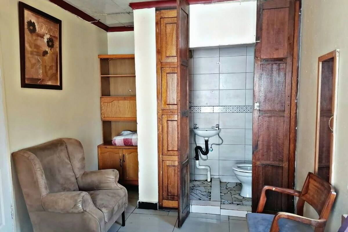Une pièce comprenant un canapé en cuir marron, un meuble en bois et une salle de bain avec des toilettes et un lavabo.