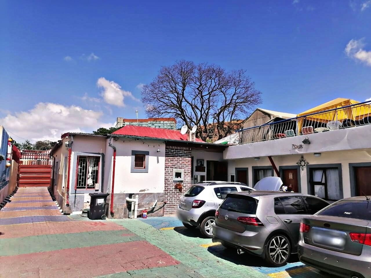 Uma rua estreita com carros estacionados e edifícios.