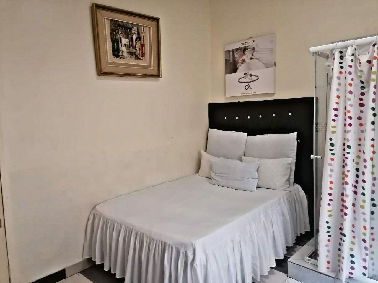 Un dormitorio con cama, un cuadro en la pared y un cartel sobre la cama.