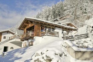 Een chalet met een houten balkon, omgeven door met sneeuw bedekte bomen.