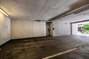 Un parking avec des murs en béton, un extincteur et une lance d’incendie fixée au mur.