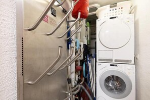 Une buanderie avec un lave-linge blanc et des barres d’appui en métal.